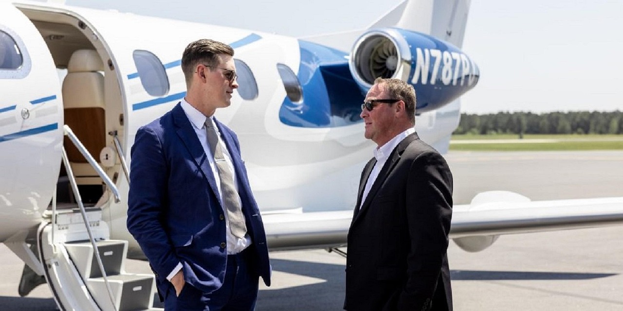 Business executives standing beside a private jet on an airport tarmac discussing aircraft ownership and expansion opportunities, representing airport hangar loans, jet refurbishment funding, aviation equipment upgrades financing, aviation acquisition financing, and aviation repair funding for private aviation operators, charter companies, and corporate aircraft owners.