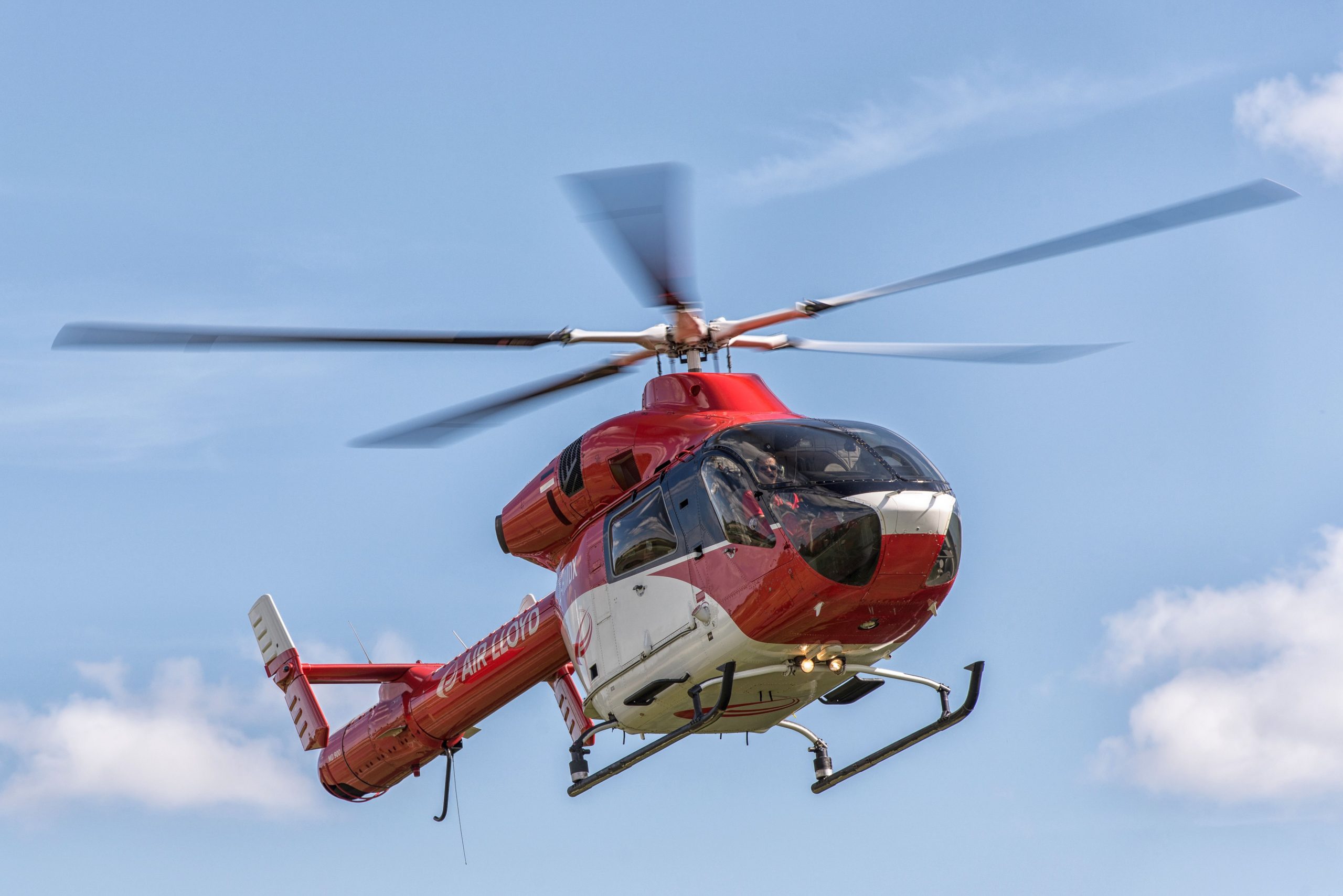 Red helicopter in flight against a blue sky representing Helicopter financing, funding an aircraft purchase, aircraft finance programs, aircraft funding solutions, and financing a used Cessna for private pilots, aviation businesses, emergency services operators, and aircraft owners seeking aviation lending options.