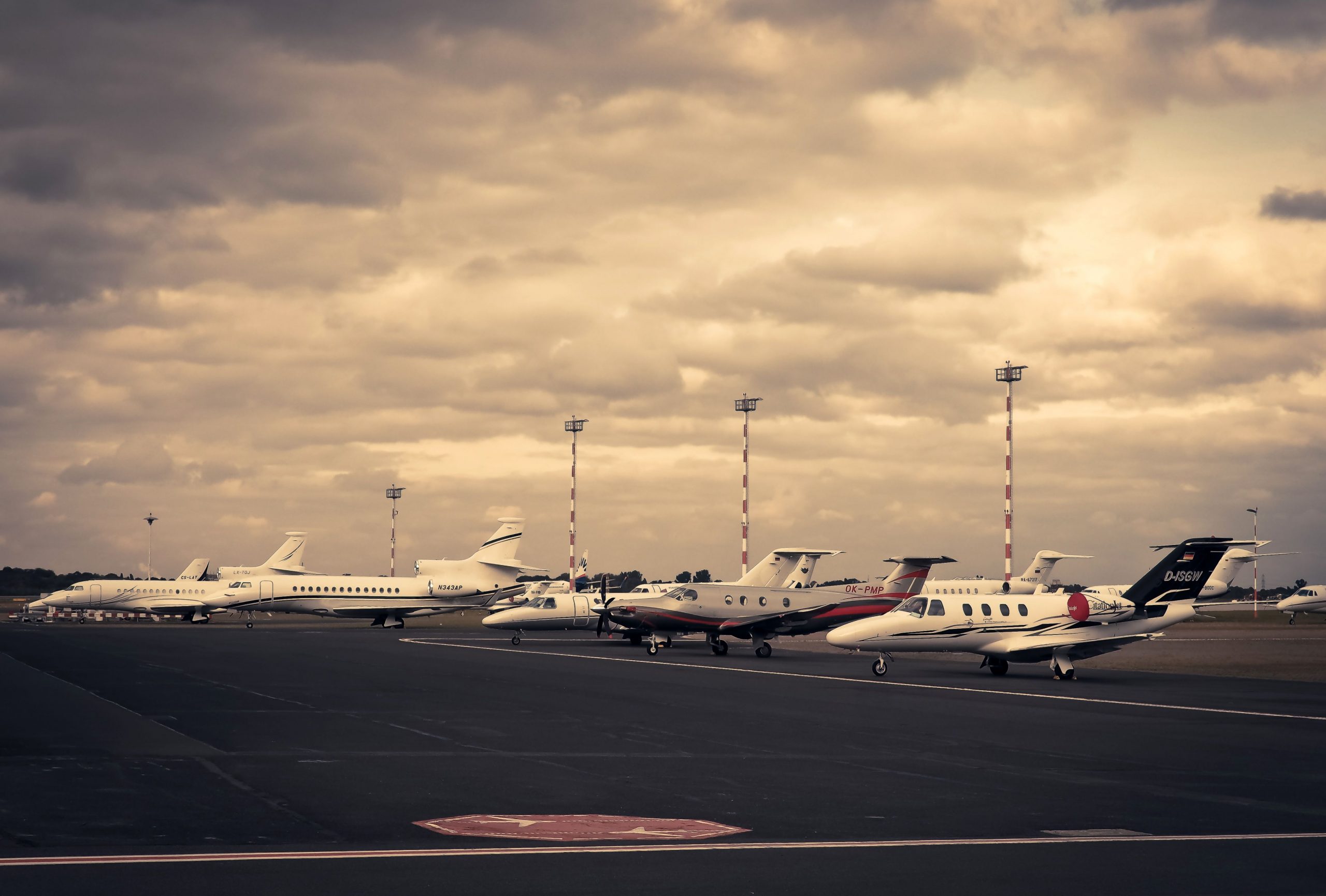 Multiple private jets and business aircraft lined up on an airport apron at sunset, representing light aircraft financing, luxury aircraft financing, business aviation financing, personal aviation financing, and executive midsize aircraft financing solutions for private owners and corporate aviation operators.