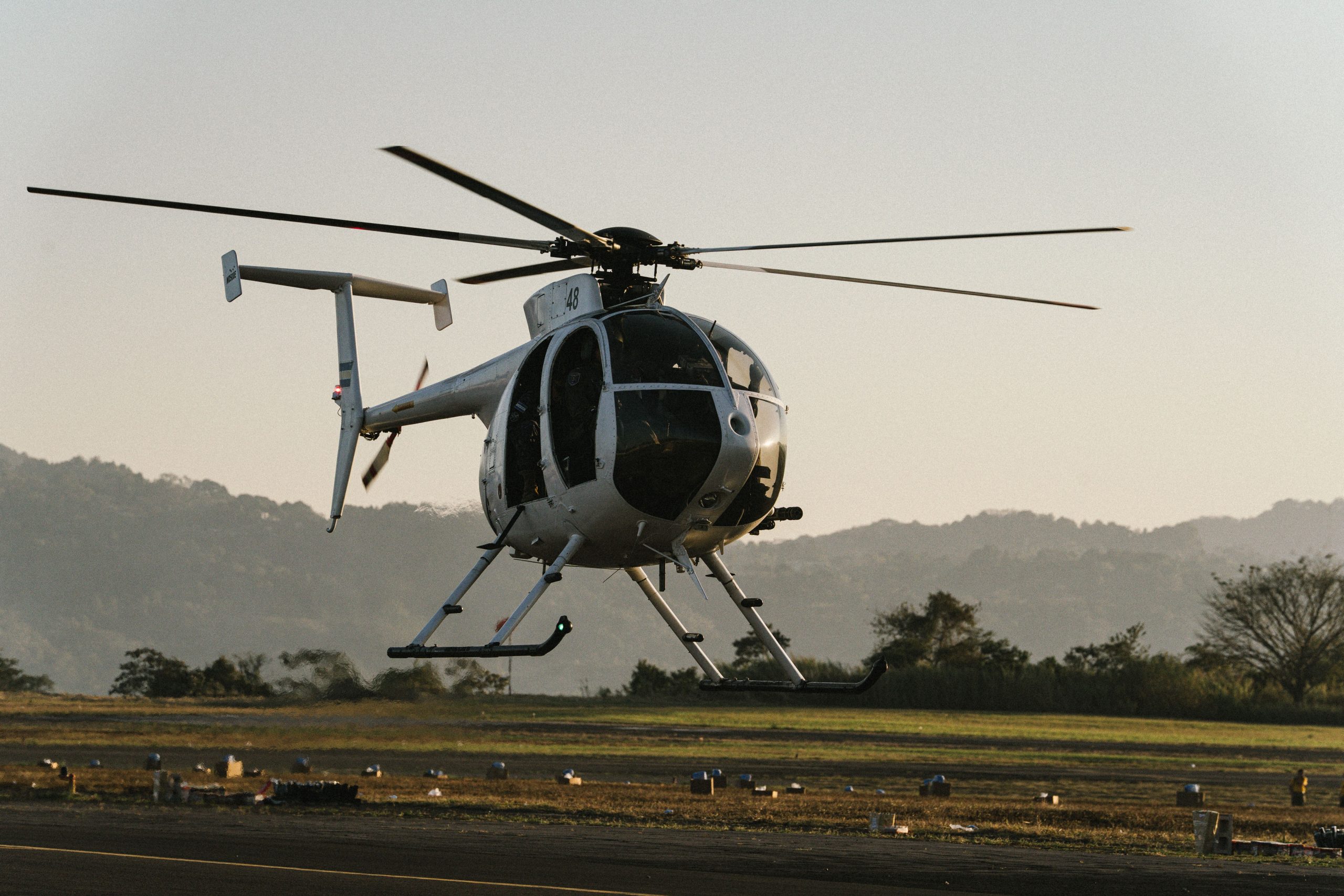 Light utility helicopter hovering above a runway at sunset, representing Piston helicopter financing, Cessna aircraft loans, aircraft hangar financing, Cessna Citation financing, and Cessna Skyhawk loan rates for aviation buyers, operators, and aircraft owners.