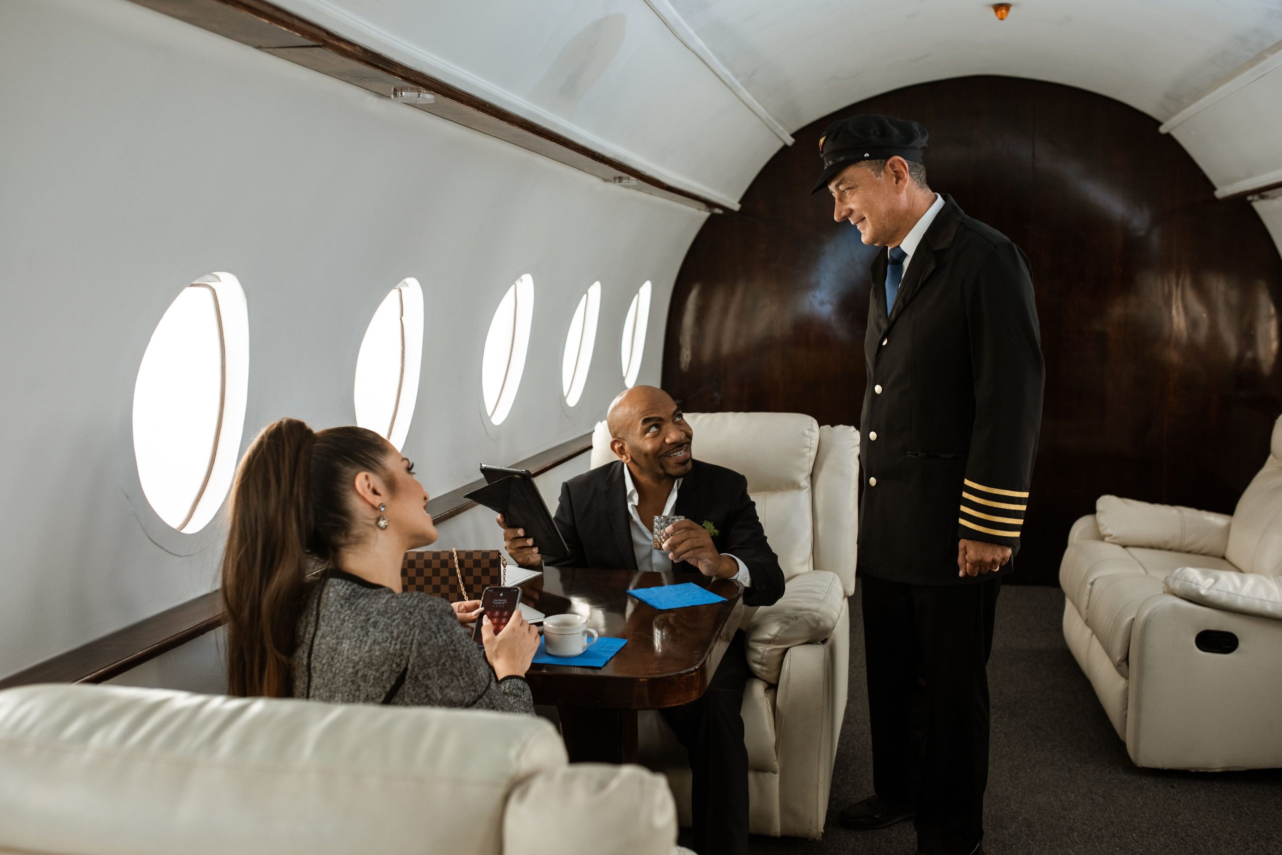 A pilot in uniform discusses options for private helicopter loans, aircraft leasing, and corporate aircraft acquisition financing with two executives seated in a luxury cabin, highlighting solutions for executive travel aircraft financing and owner pilot jet financing.